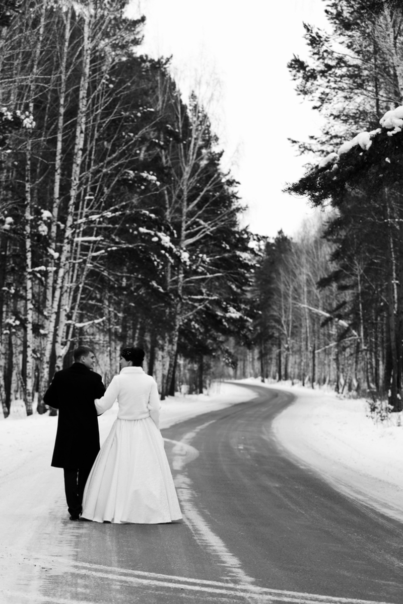Die Winterhochzeit - Brautpaar auf einsamer schneebedeckter Straße