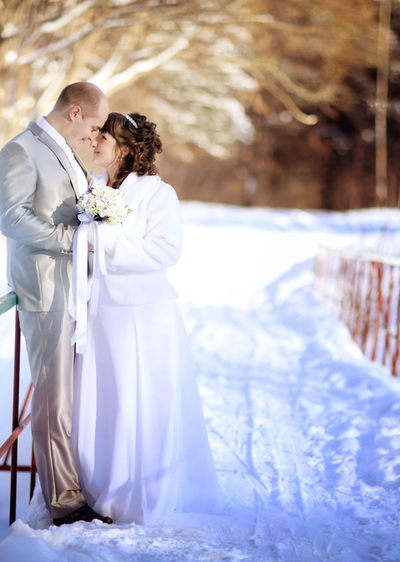 Die Winterhochzeit - Küssendes Brautpaar auf verschneiter Brücke